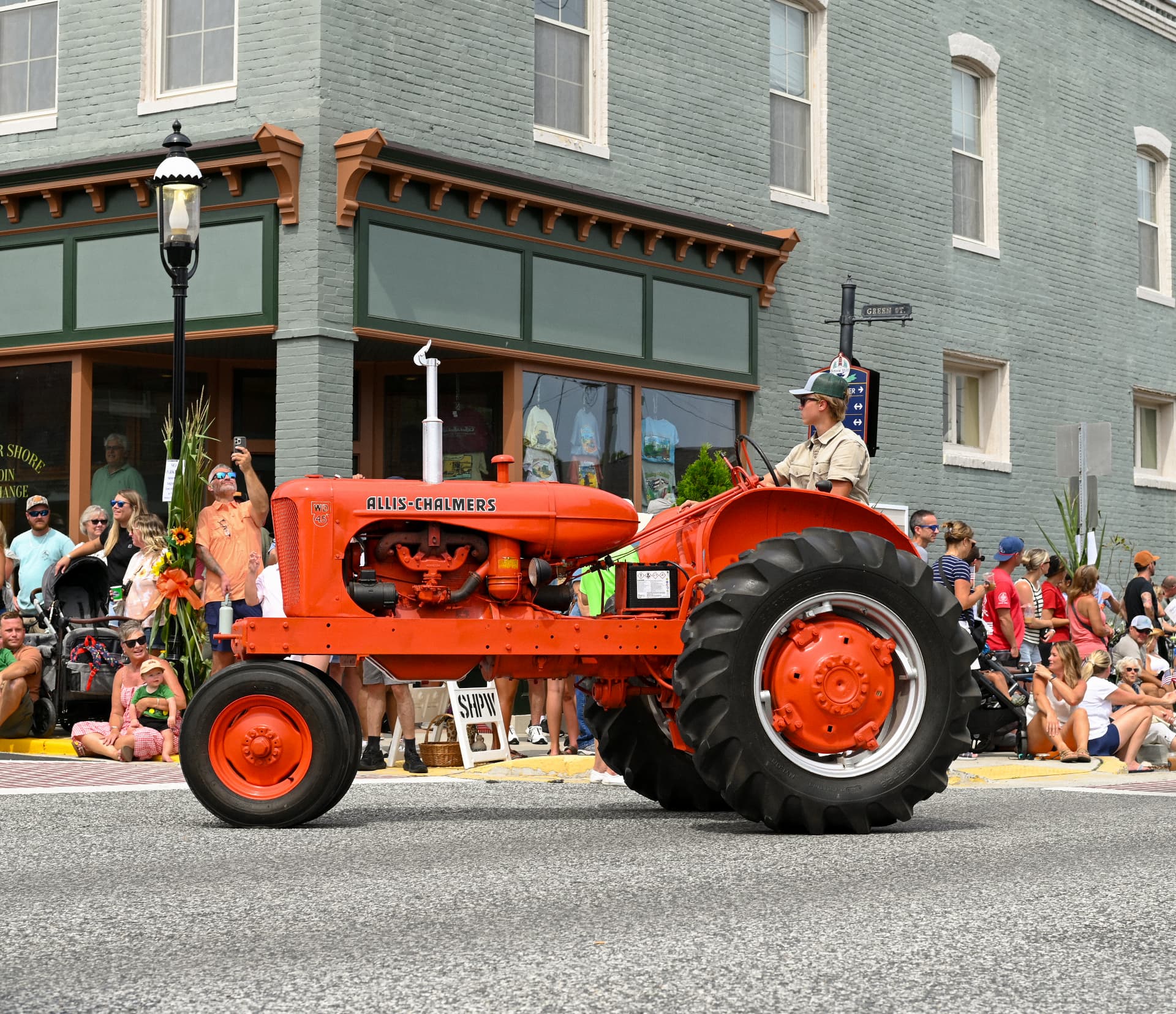 LSCEX storefront during a town parade with a vintage orange tractor passing by